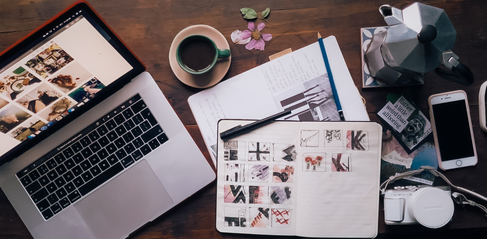 An overhead view of the Tapestry & Tales workspace with sketches, coffee and camera, capturing the early stages of design.